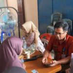 Kepala Bidang (Kabid) Perlindungan dan Jaminan Sosial Dinsos PPU, Peri Tangdirerung saat mendampingi masyarakat yang mengalami kesulitan mengakses aplikasi. (doc.diskominfoppu)